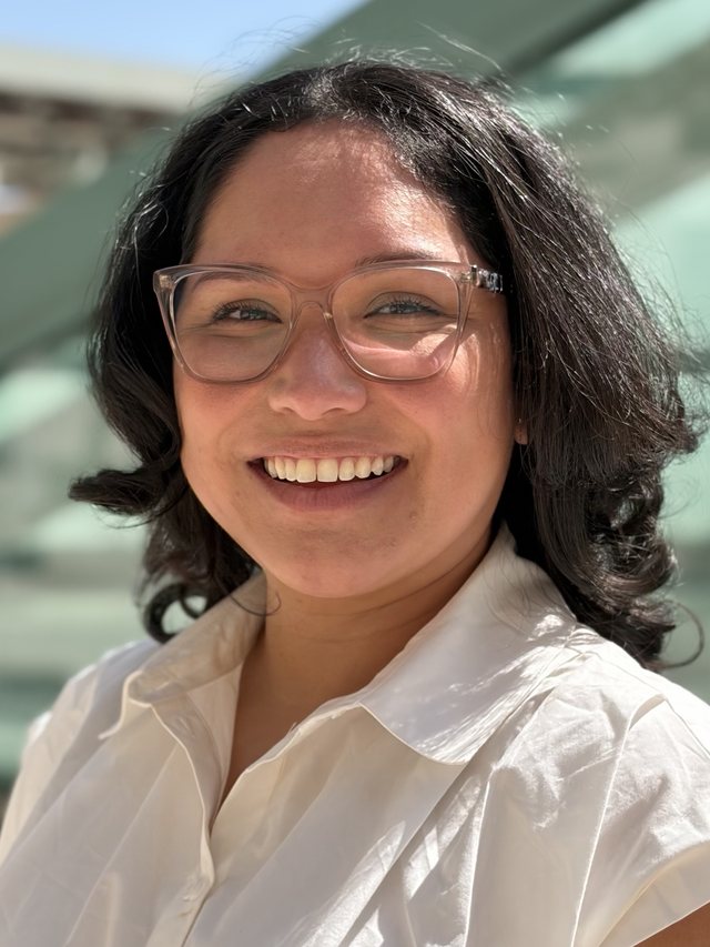 Crystal Olivas-Rasmussen, smiling, wearing clear-framed glasses and a white collared blouse